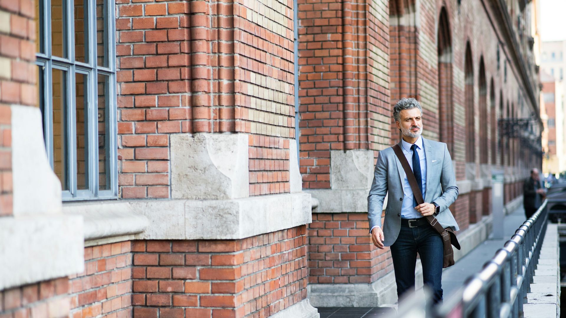 Manager idzie wzdłuż ceglanego budynku